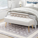 Beige tufted bench with gold legs in a bedroom setting