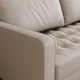 Close-up of a beige leather sofa with tufted backrest