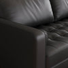 Close-up of a black leather sofa with tufted design