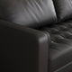 Close-up of a black leather sofa with tufted design