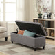 Gray storage bench with open lid revealing pillows in a living room setting.