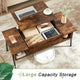 Wooden coffee table with storage compartments, laptop, tablet, and phone on a patterned rug.