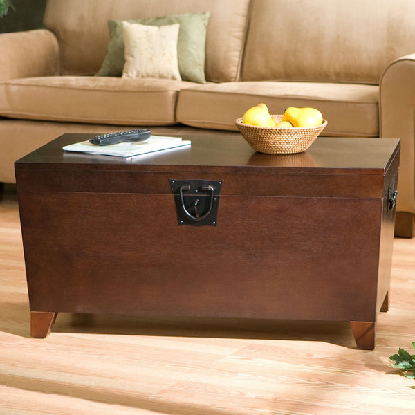 Brown wooden coffee table with a basket of fruit and remote controls in a living room setting.
