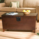 Brown wooden coffee table with a basket of fruit and remote controls in a living room setting.