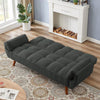 Dark gray sofa bed in a living room with a fireplace and rug.