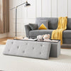 Gray sofa with yellow blanket and pillows, gray tufted bench, and floor lamp in a living room.