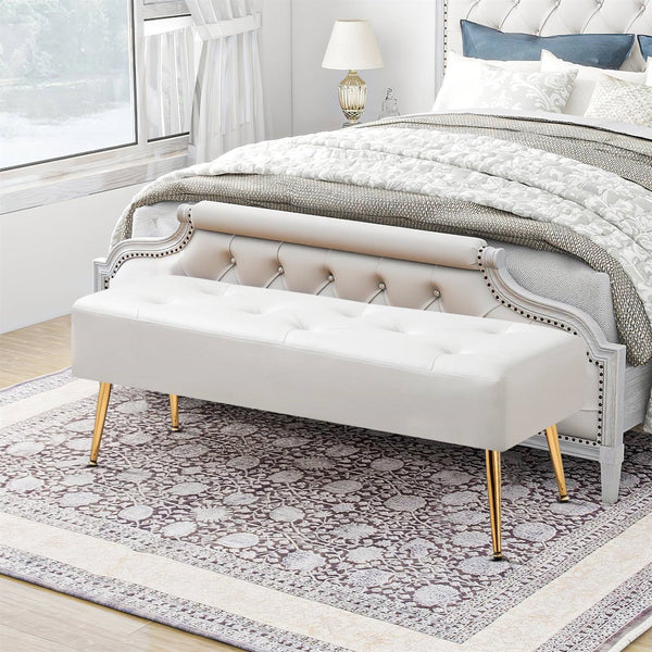 Beige tufted bench with gold legs in a bedroom setting