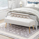Beige tufted bench with gold legs in a bedroom setting