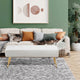 Living room with a beige sofa, white ottoman, and decorative pillows against a green wall.