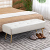 White upholstered bench with gold legs in a bedroom setting.