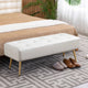 White upholstered bench with gold legs in a bedroom setting.