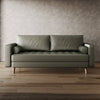 Green leather sofa in a room with wooden flooring and a textured wall.