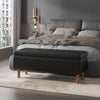 Black upholstered bench in front of a gray bed in a modern bedroom.