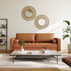 Brown leather sofa in a living room with decorative mirrors and a coffee table.