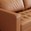 Close-up of a brown leather sofa with tufted backrest