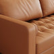Close-up of a brown leather sofa with tufted backrest