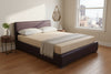 Beige mattress on a purple bed frame inside an apartment bedroom in a metro area