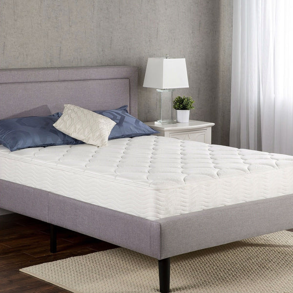 Mattress topper on a bed in a bedroom setting with a lamp and plant.